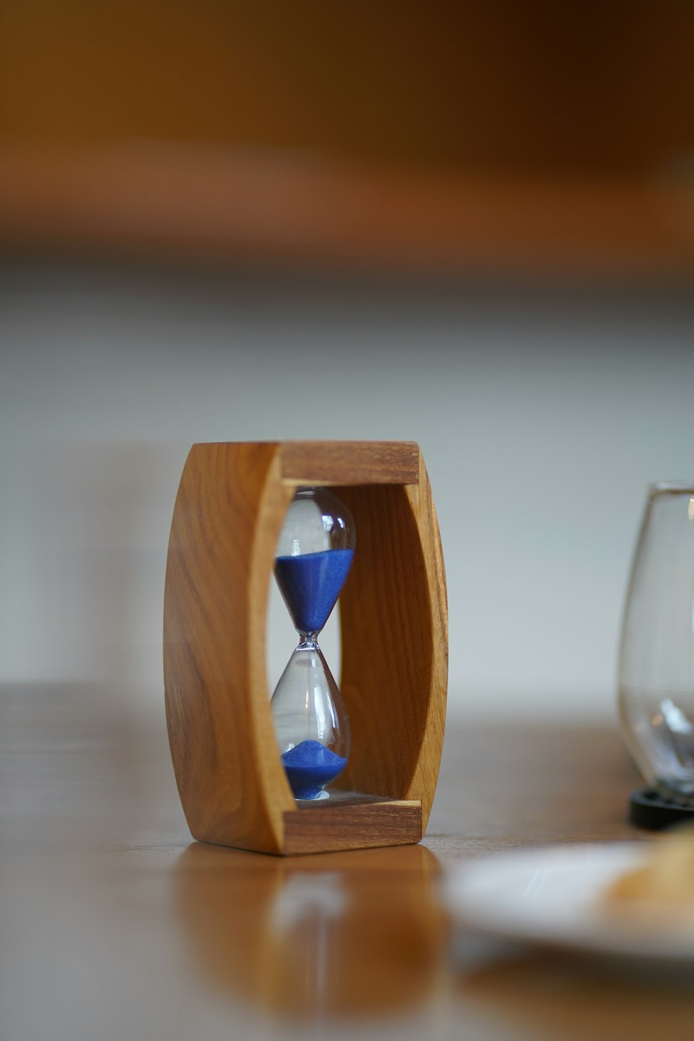 an hourglass sitting on a table next to a wine glass