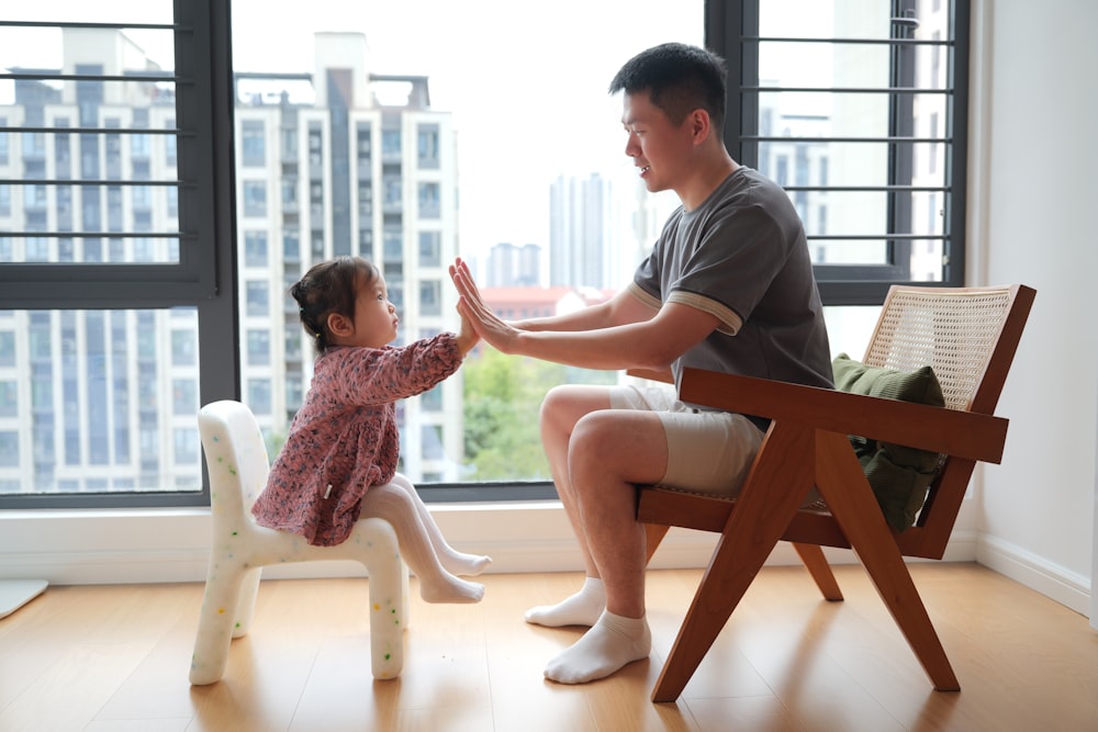 a man sitting in a chair next to a little girl