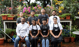 a group of people sitting on a bench in front of potted plants