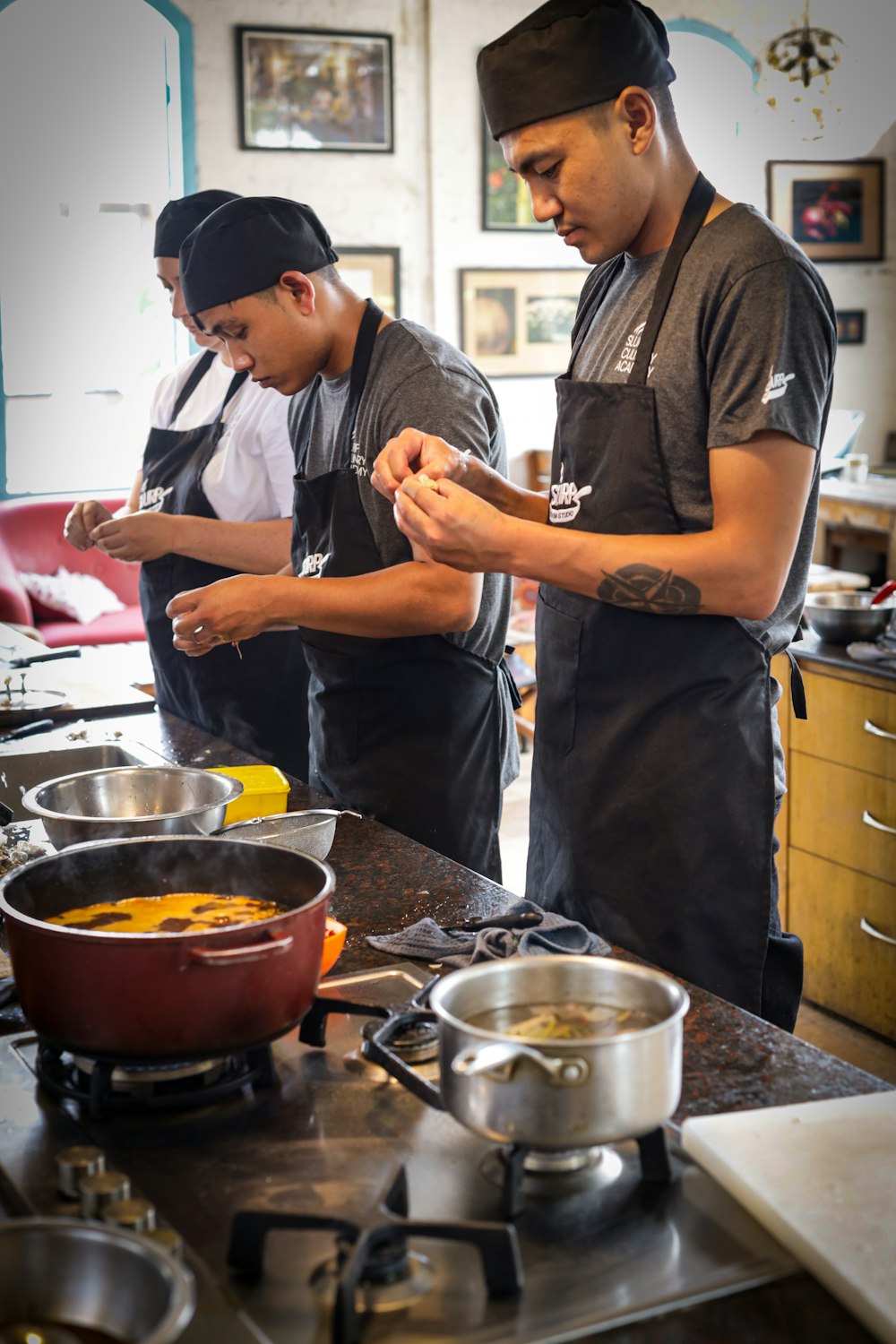 a couple of men standing in a kitchen preparing food