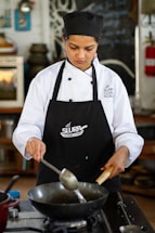 a woman in a chef's uniform cooking food on a stove