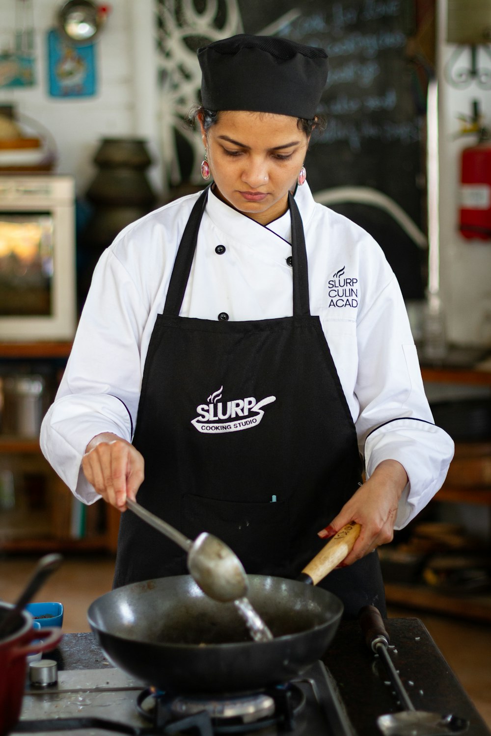 Una mujer con uniforme de chef cocinando comida en una estufa
