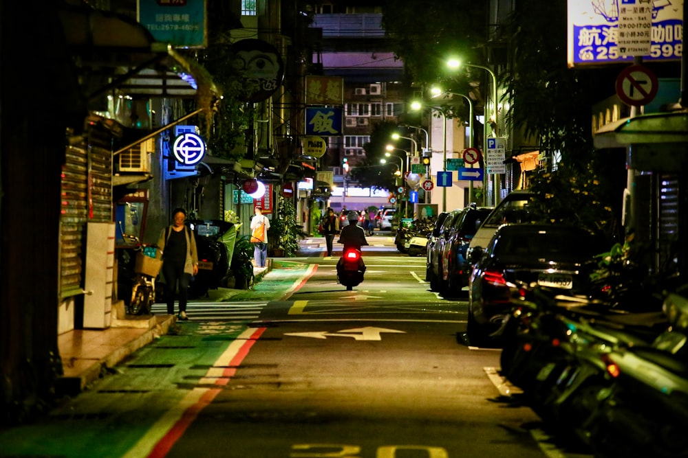 a city street at night with cars parked on both sides of the street