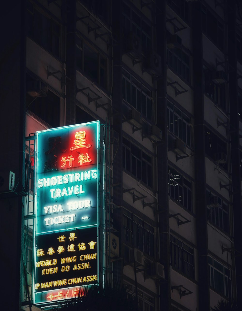 a neon sign in front of a tall building