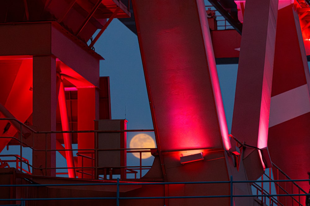 a full moon is seen through the red lights of a building
