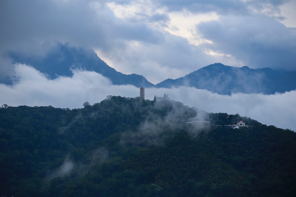a mountain covered in clouds with a tower on top