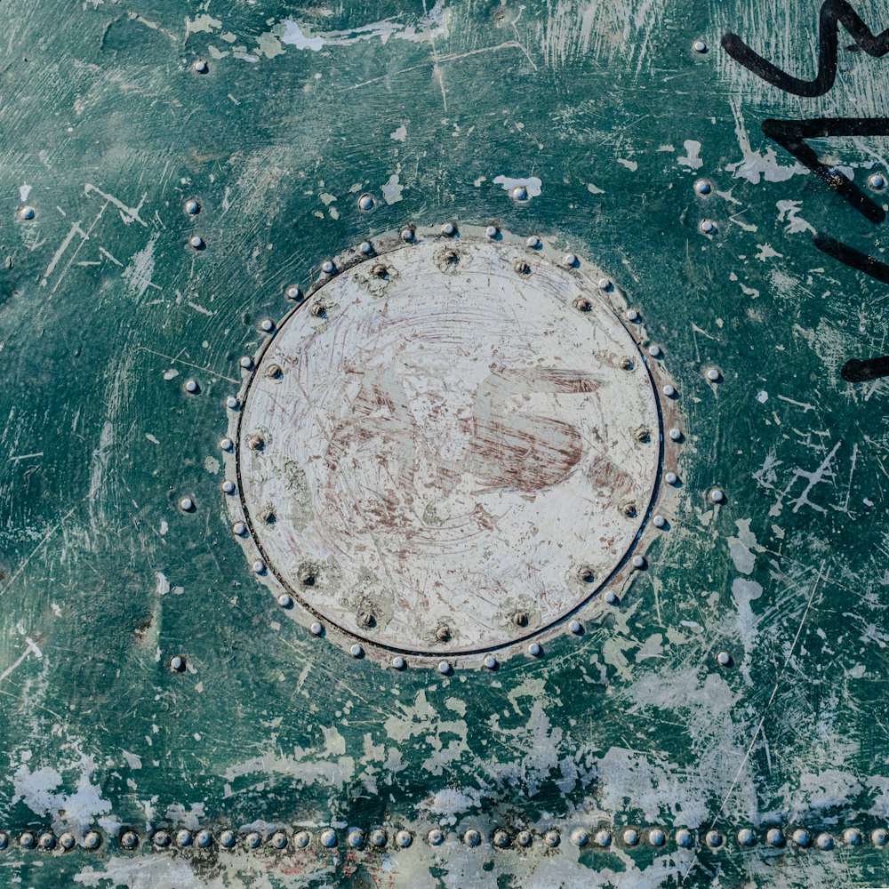 a close up of a green and white wall with a circular design on it