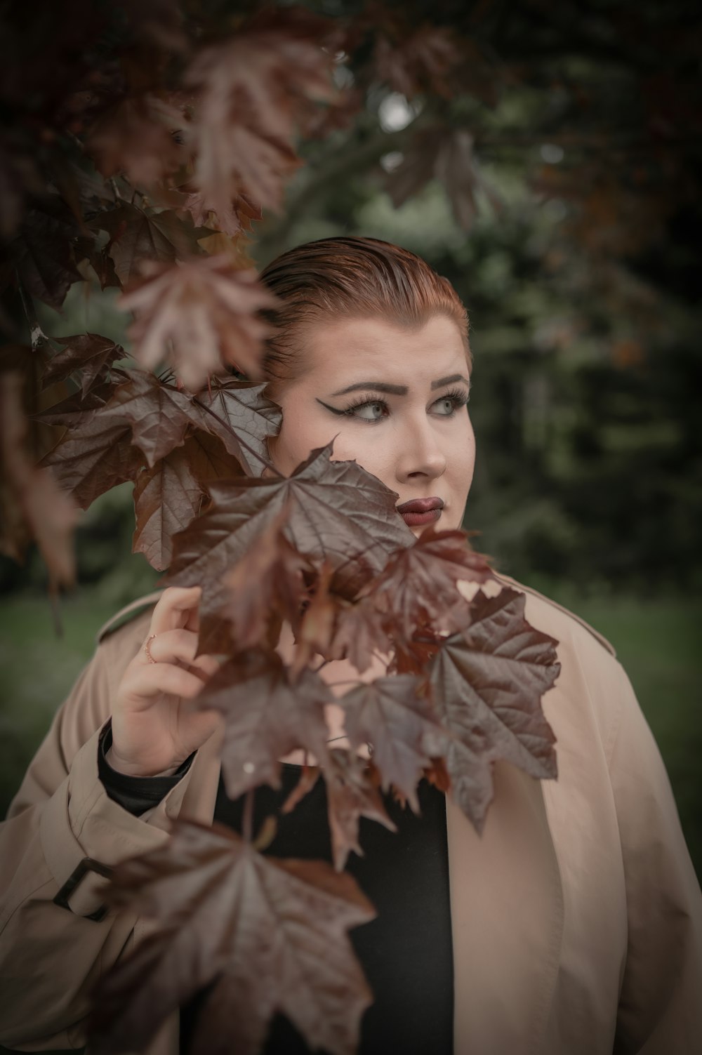 a woman holding a leaf in front of her face