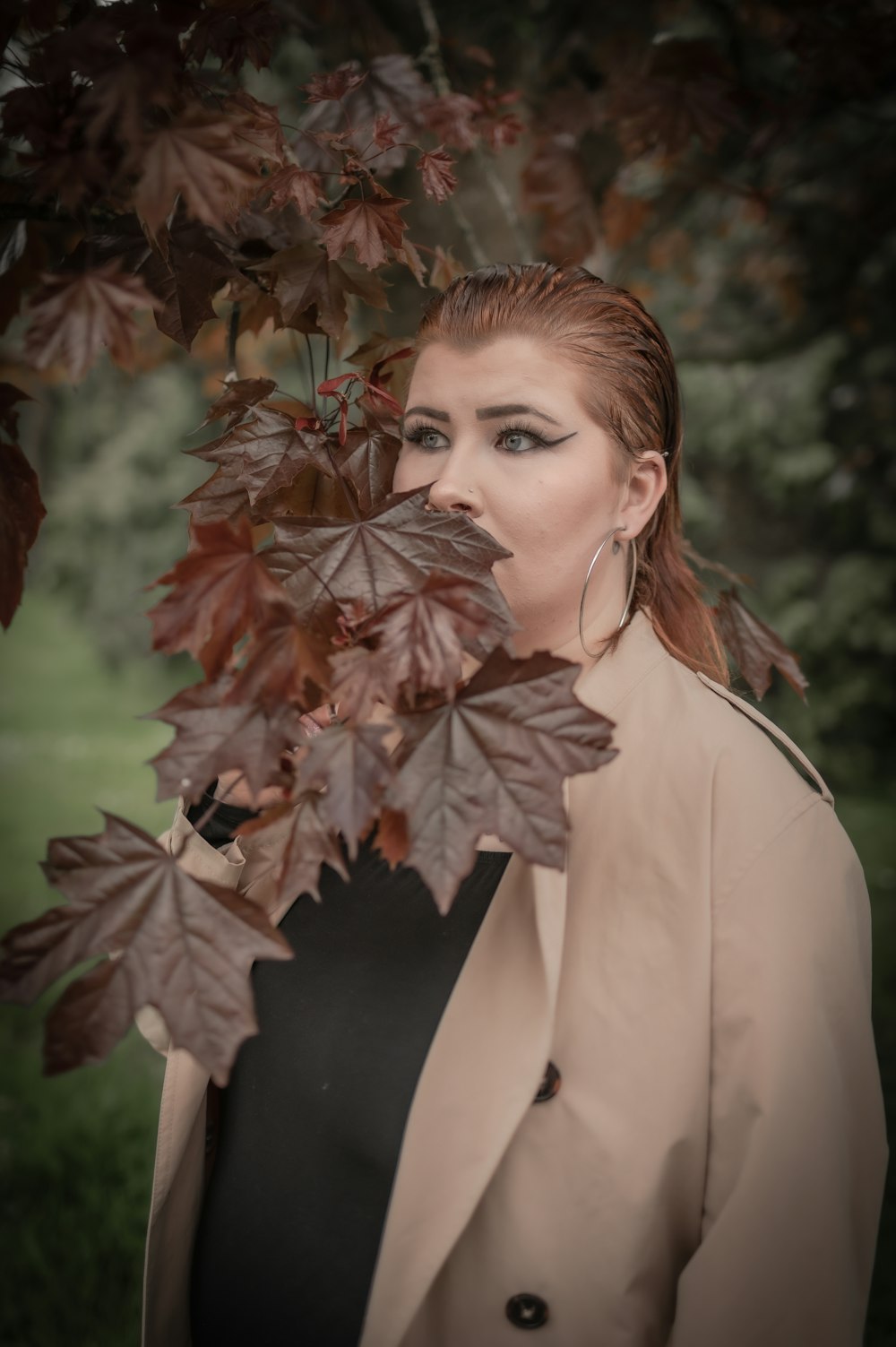 a woman standing under a tree with leaves