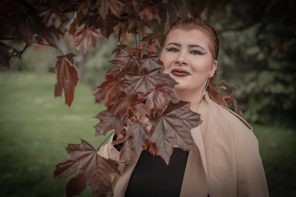 a woman standing under a tree with leaves