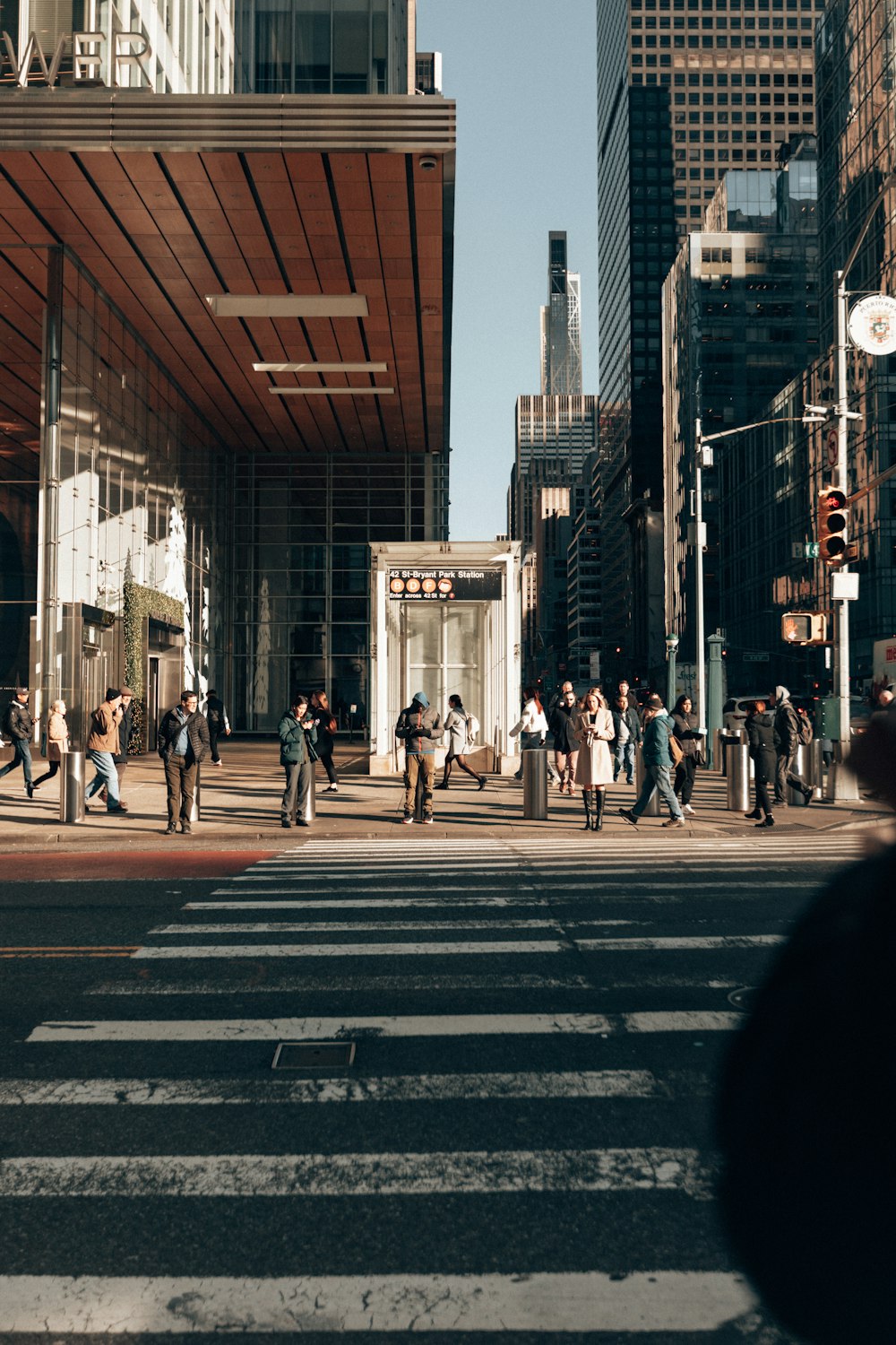 a group of people walking across a street next to tall buildings