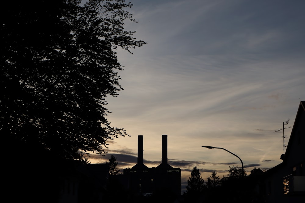 the silhouette of two smoke stacks against a dusk sky