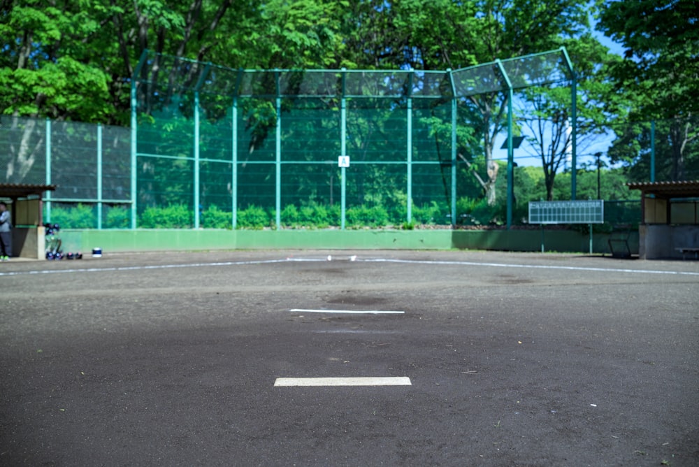 a baseball field with a fence and trees in the background