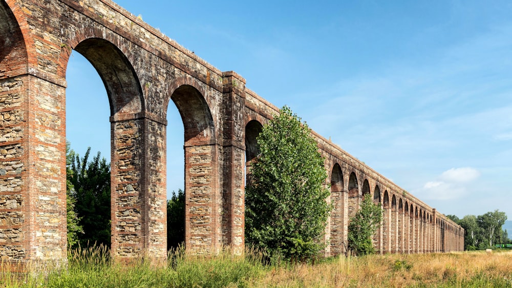 an old brick train bridge over a grassy field