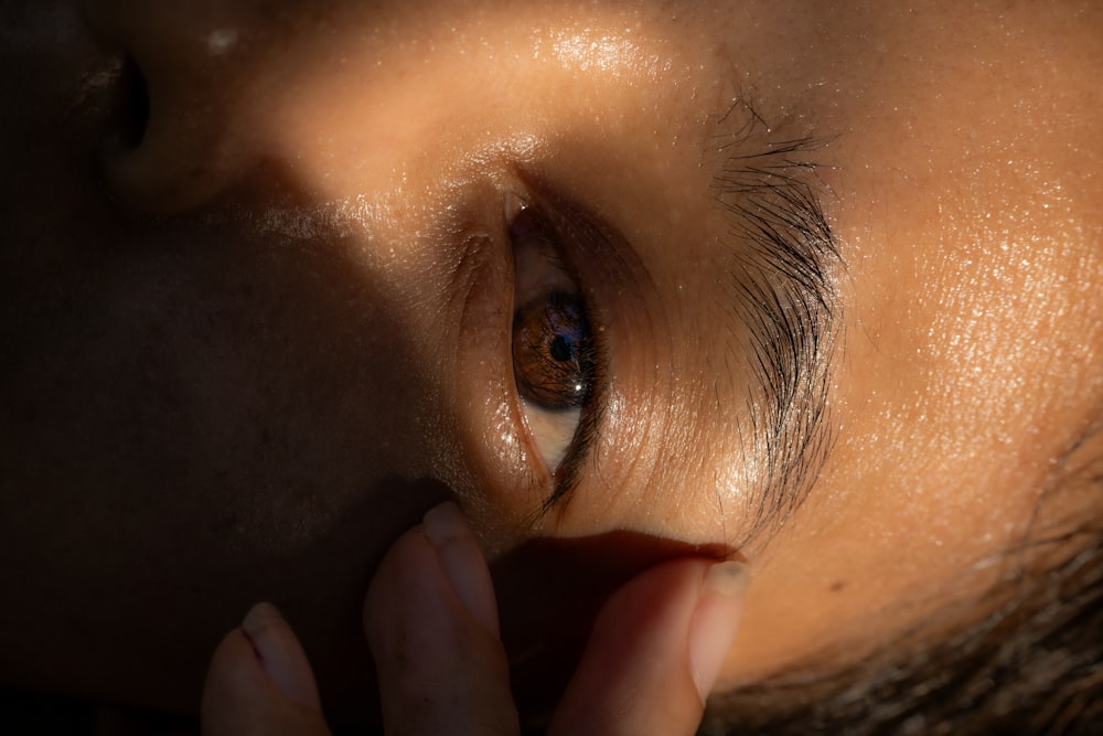 a close up of a person's eye with their hand on the side of