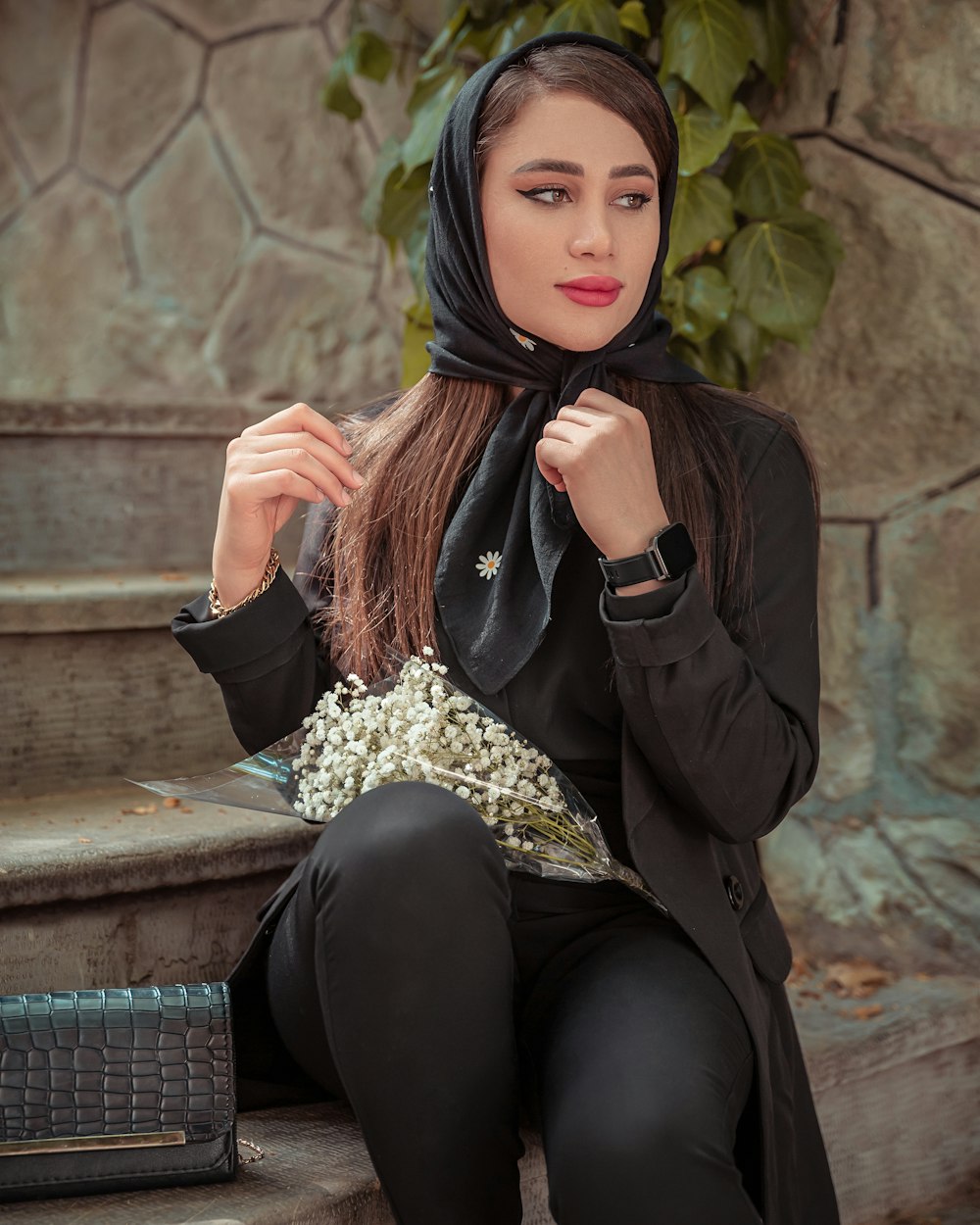 a woman sitting on a step wearing a black hijab