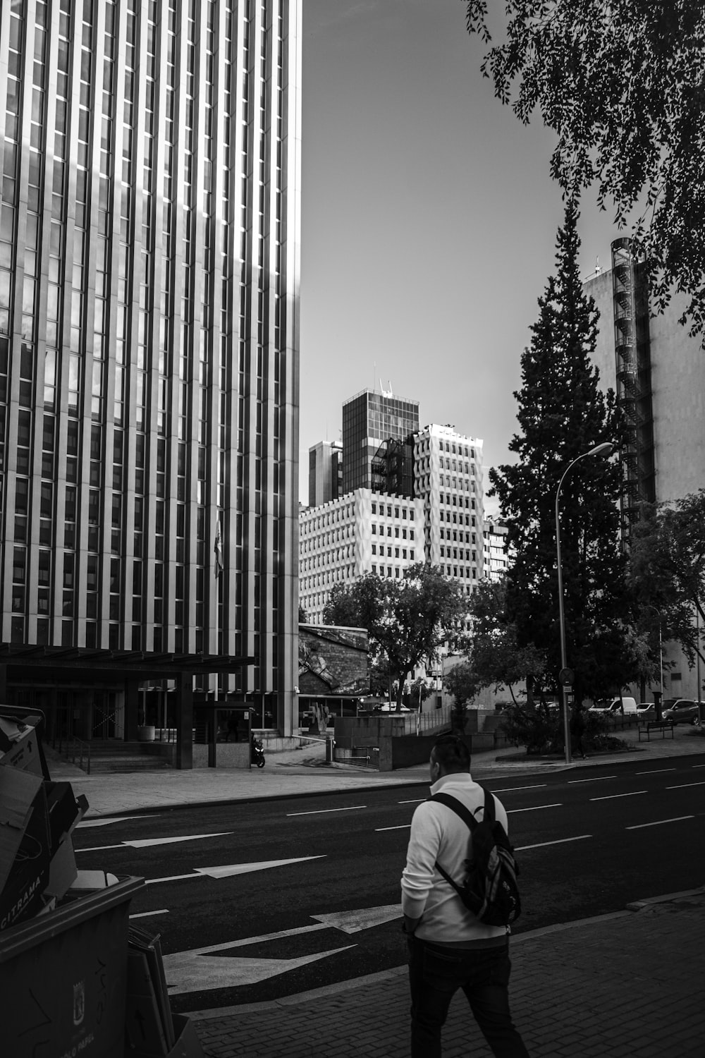 a man walking down a sidewalk next to tall buildings