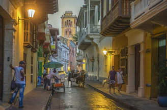 a group of people walking down a street next to tall buildings