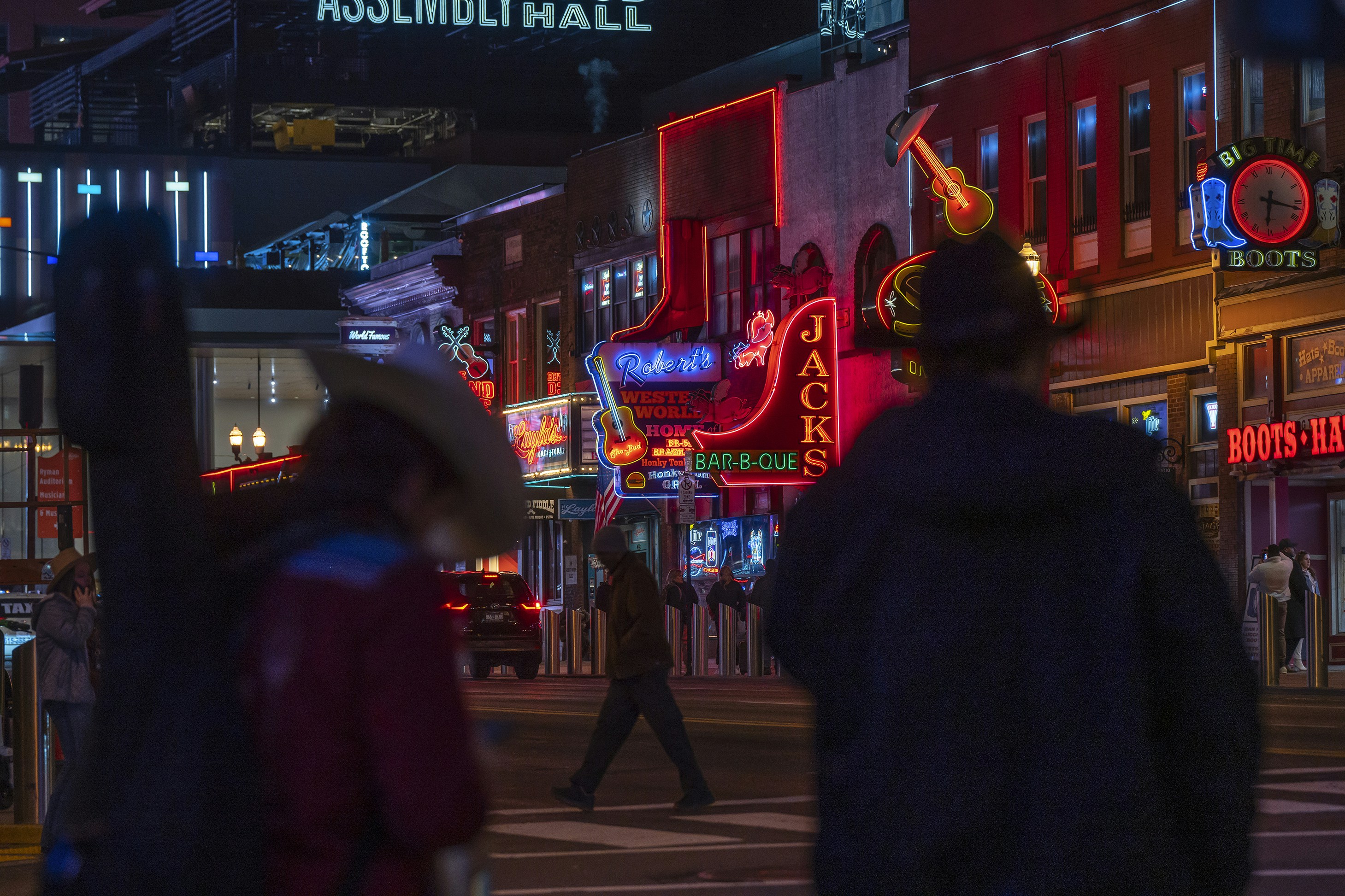 a couple of people walking across a street at night