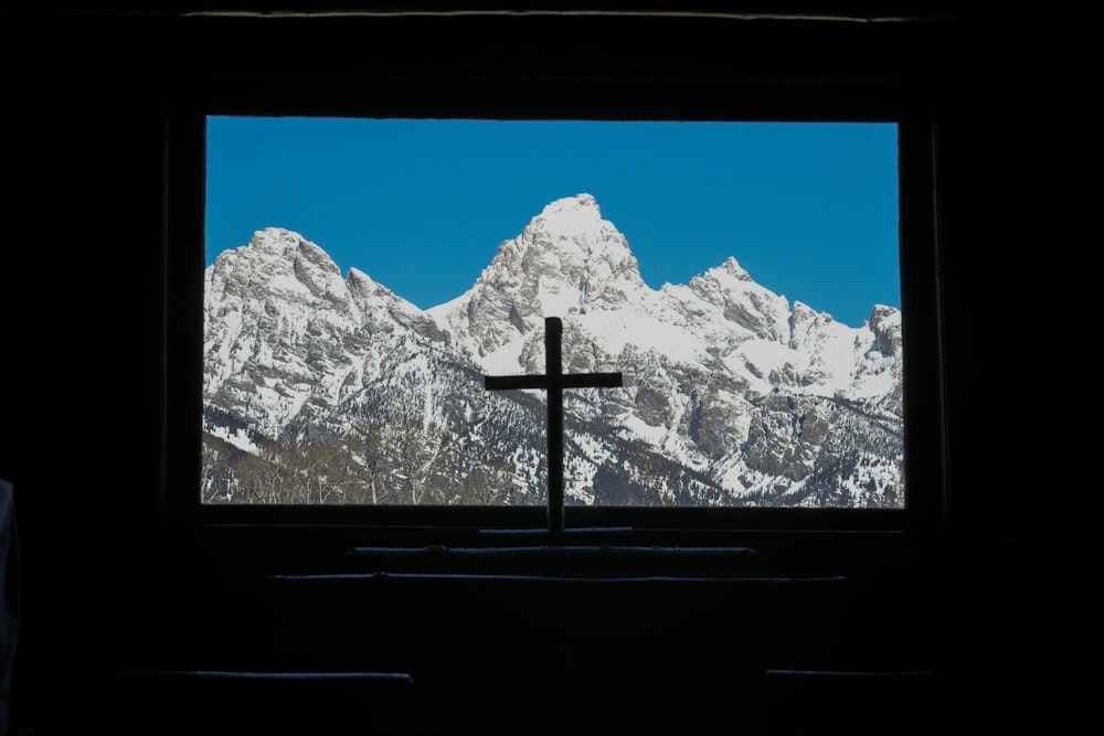 a cross in front of a window with mountains in the background