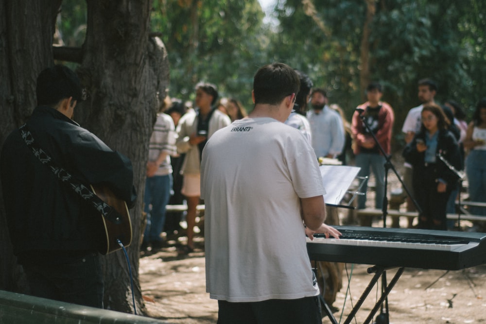 a man playing a keyboard in front of a group of people