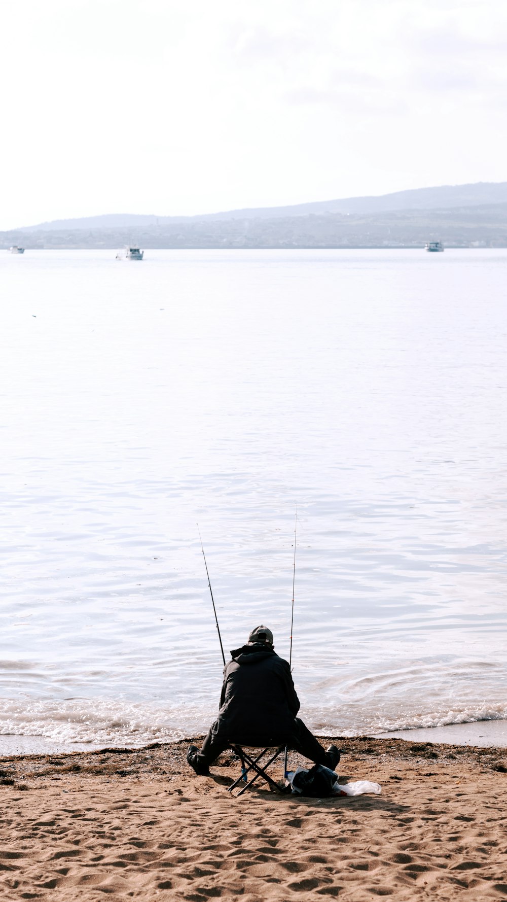a person sitting on a beach with a fishing pole