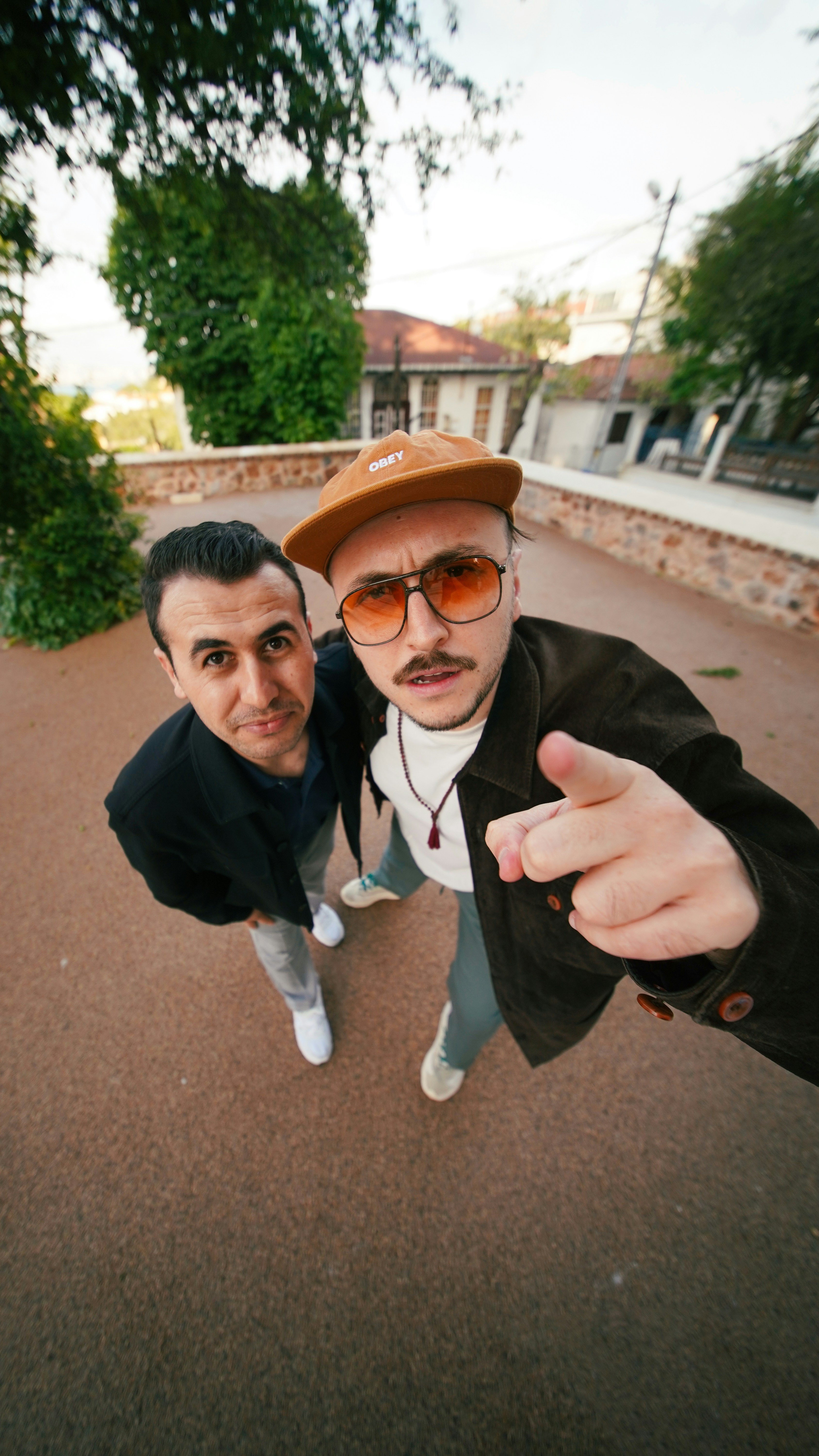 Two men posing for a wide-angle shot outdoors