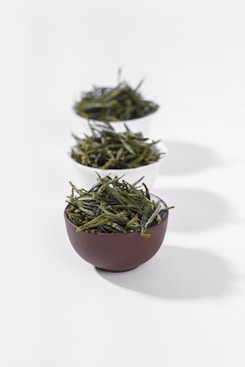 three bowls filled with green tea on a white surface
