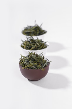 three bowls filled with green tea on a white surface