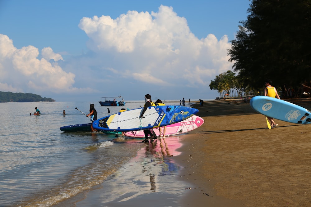 a group of people standing on top of a beach next to surfboards