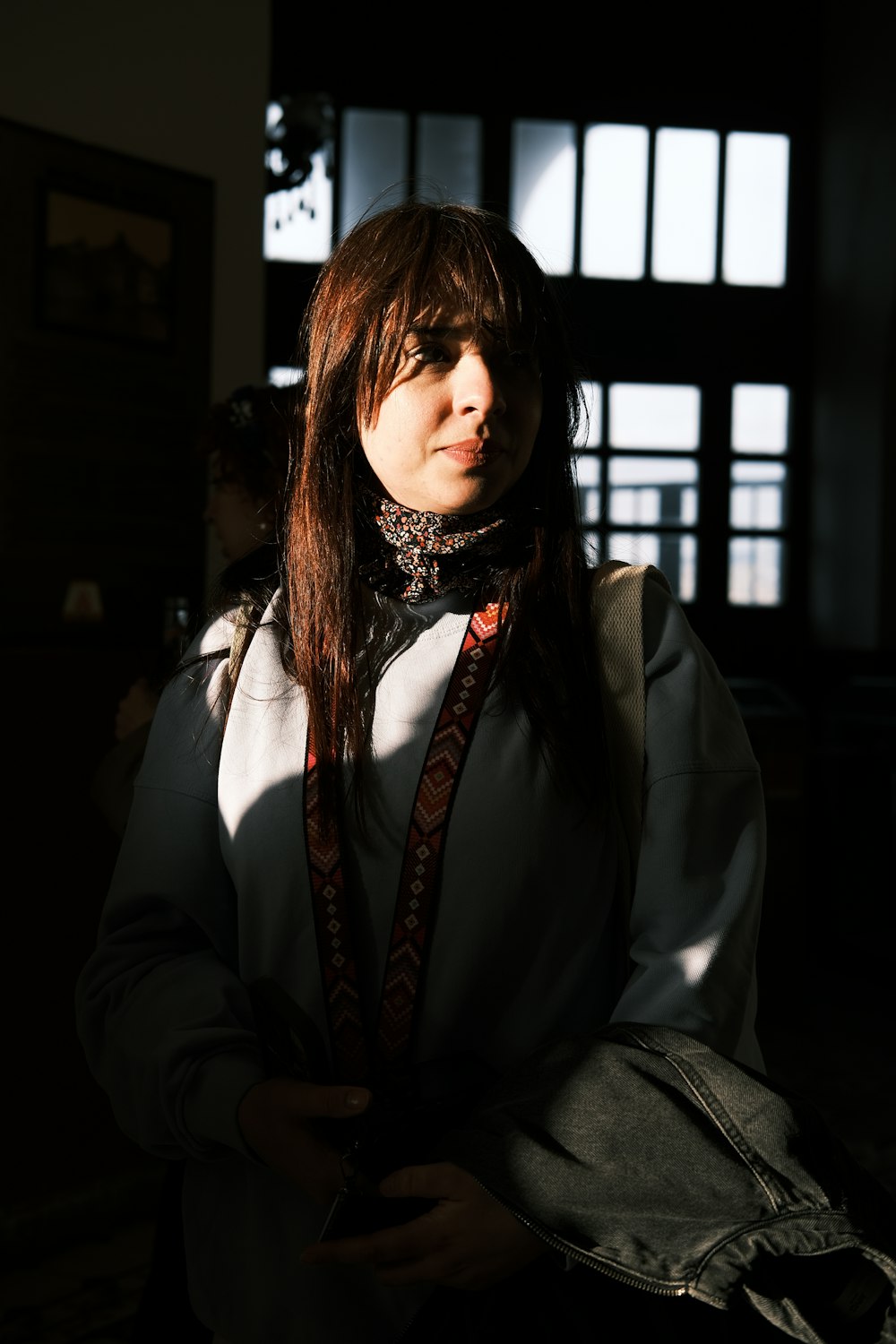 a woman standing in a dark room with a tie around her neck