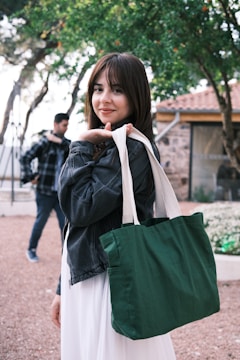 a woman in a white dress holding a green bag