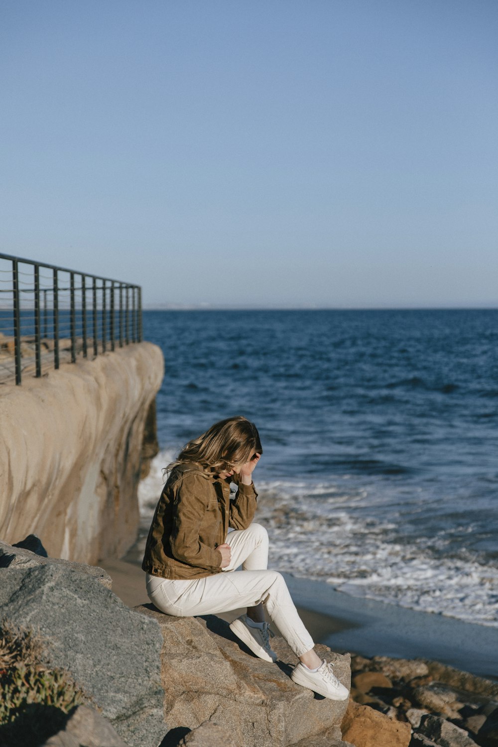 a woman sitting on a rock next to the ocean