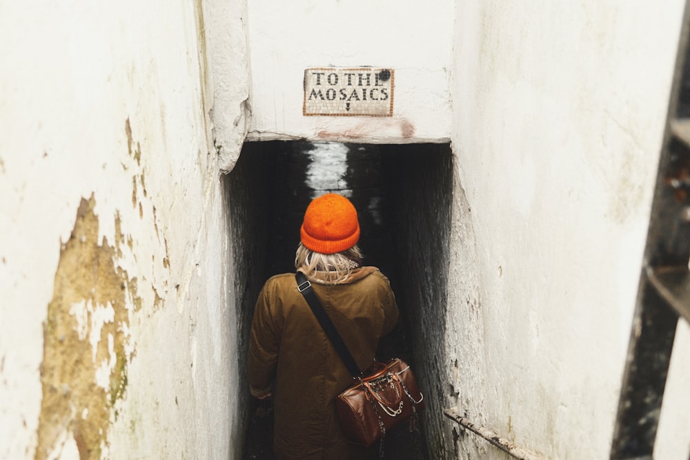 a person with an orange hat walking into a tunnel