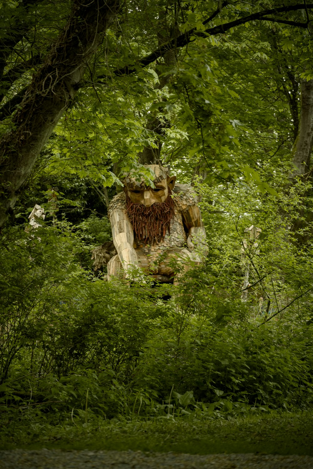 a statue in the middle of a lush green forest