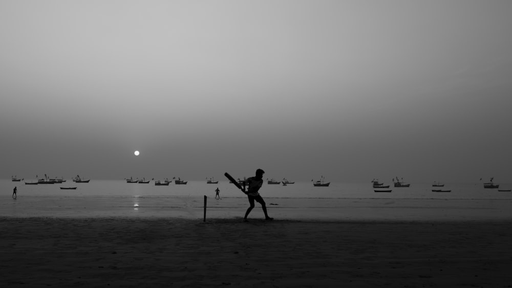 a person standing on a beach holding a bat