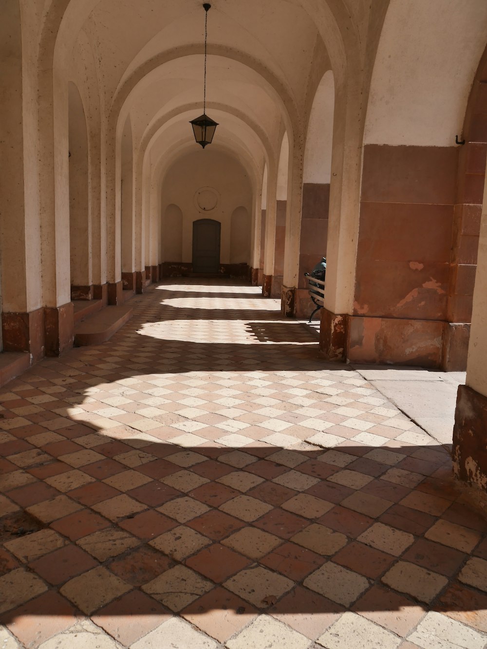 a long hallway with a checkered floor and a lantern hanging from the ceiling