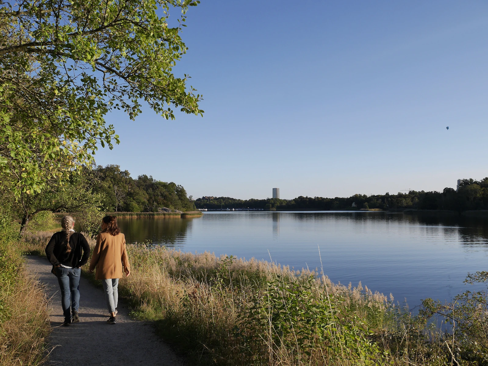 Zwei Menschen gehen an einem ruhigen See entlang als Symbol für Bewegung und Abstand bei innerer Unruhe nach Rauchstopp