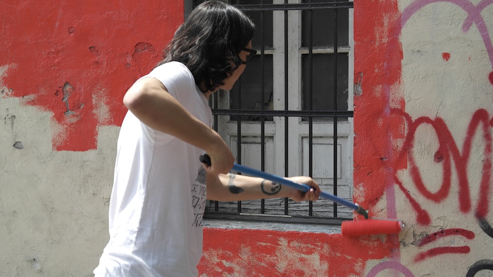 a man holding a paint roller in front of a window