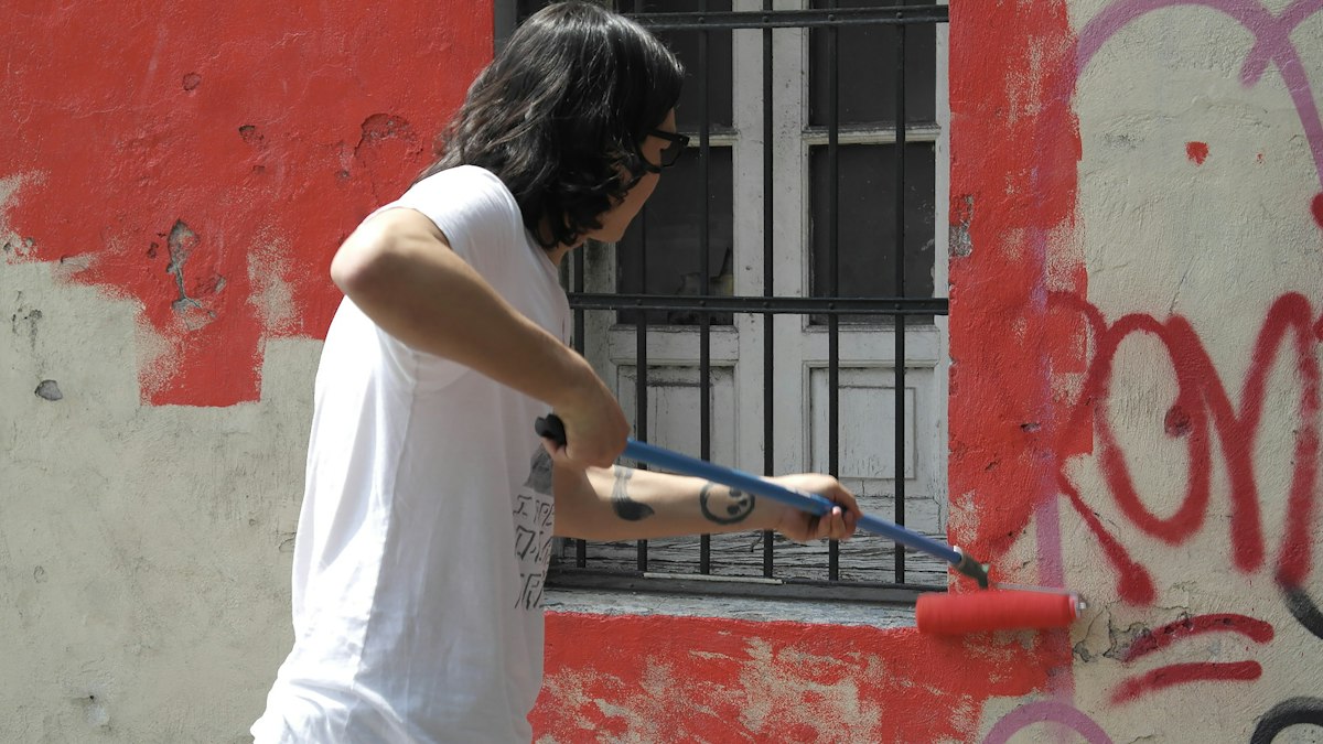 A person holding a paint roller beside an open window