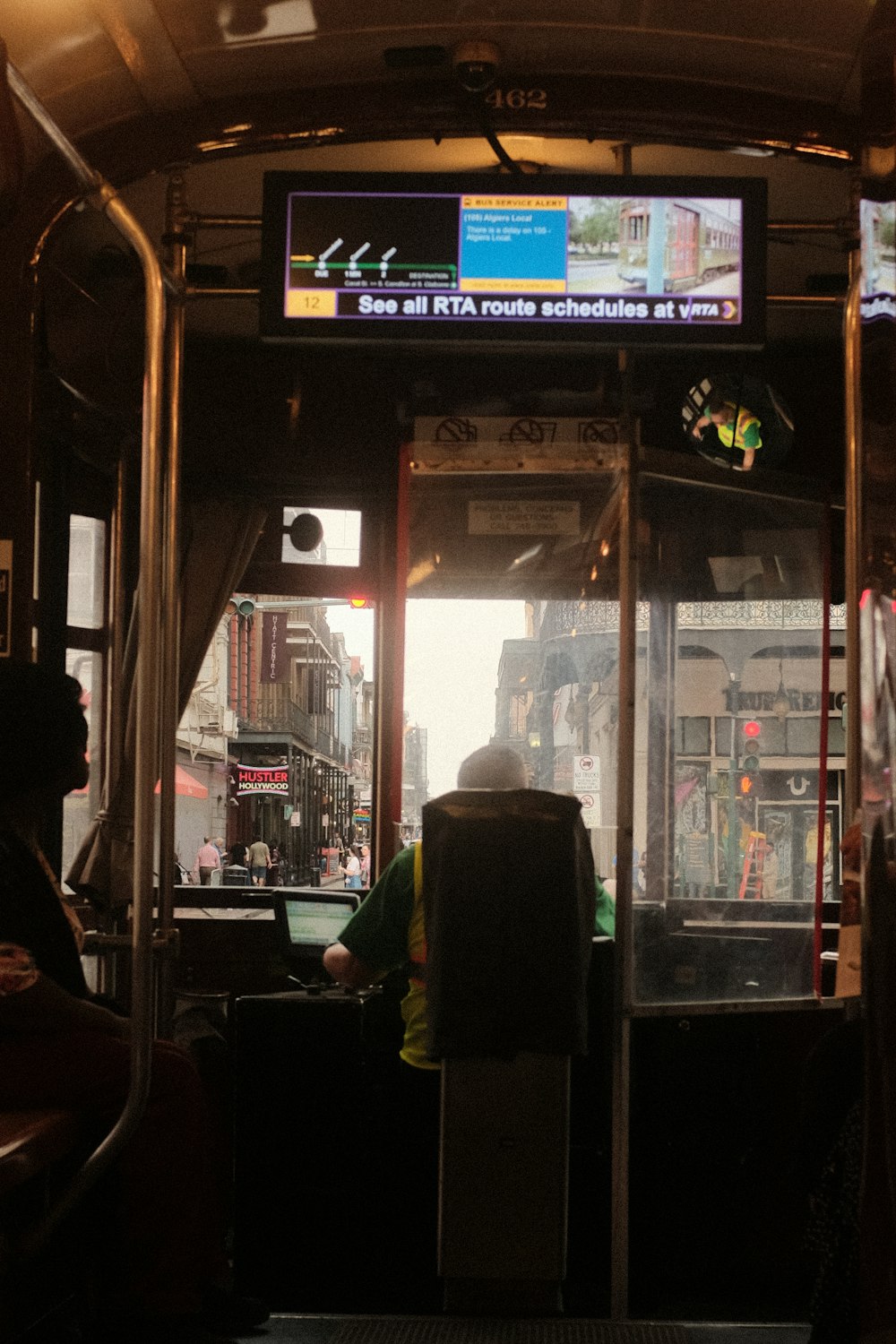 uma pessoa sentada em um ônibus com uma TV acima da cabeça