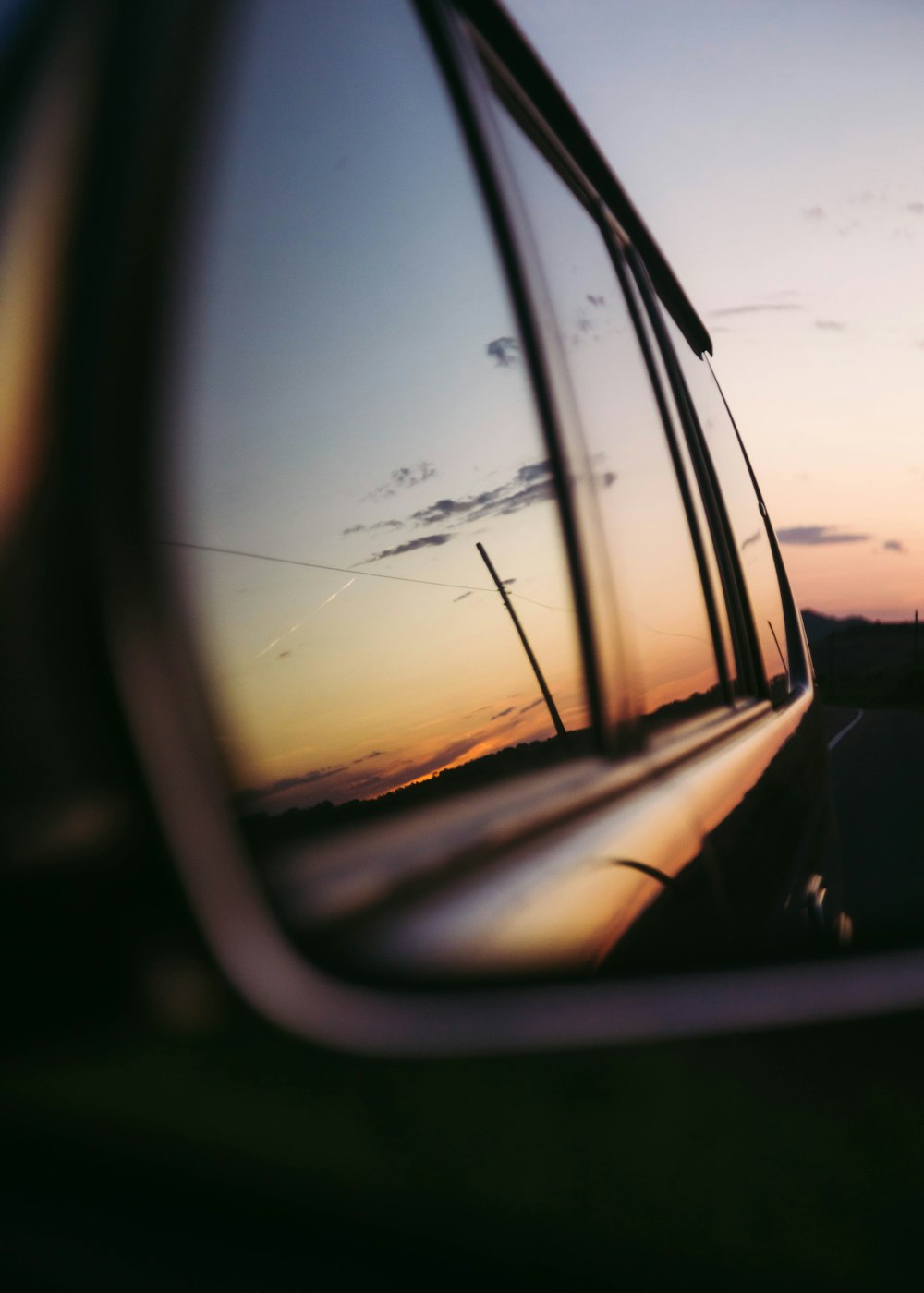 a rear view mirror reflecting a sunset in the side view mirror