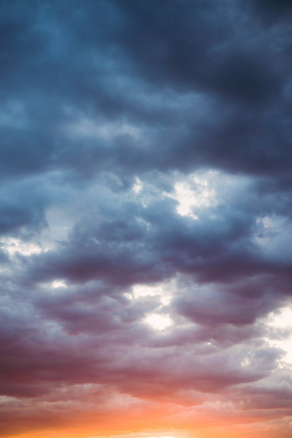 a couple of people standing on top of a beach under a cloudy sky