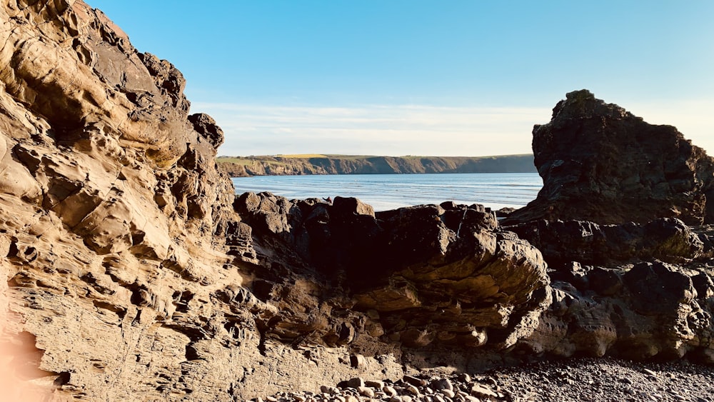 a rocky cliff with a body of water in the background