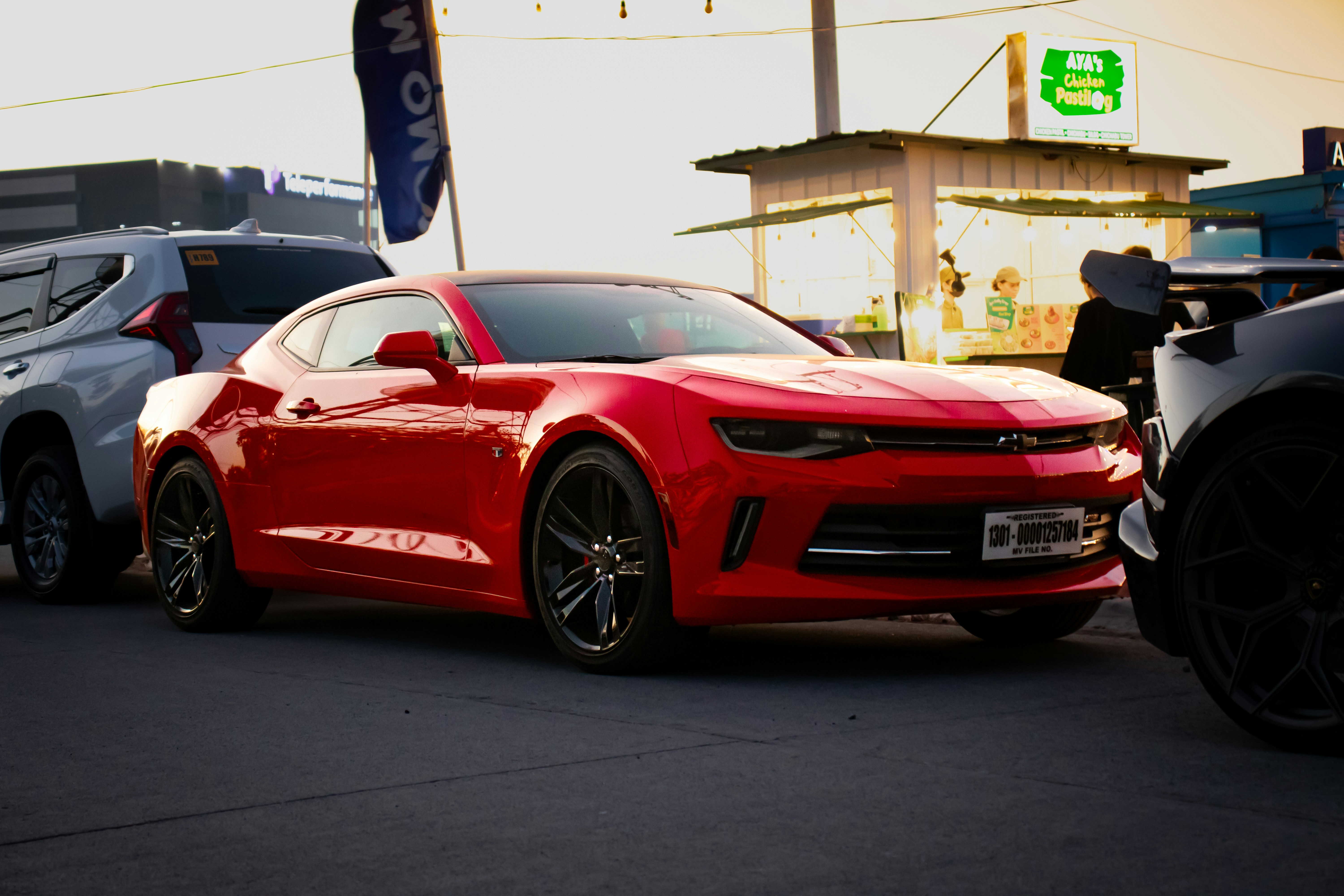 a red chevrolet camaro is parked in front of a gas station