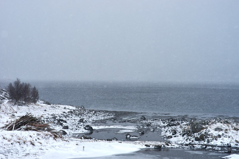 a snow covered field with a body of water in the distance