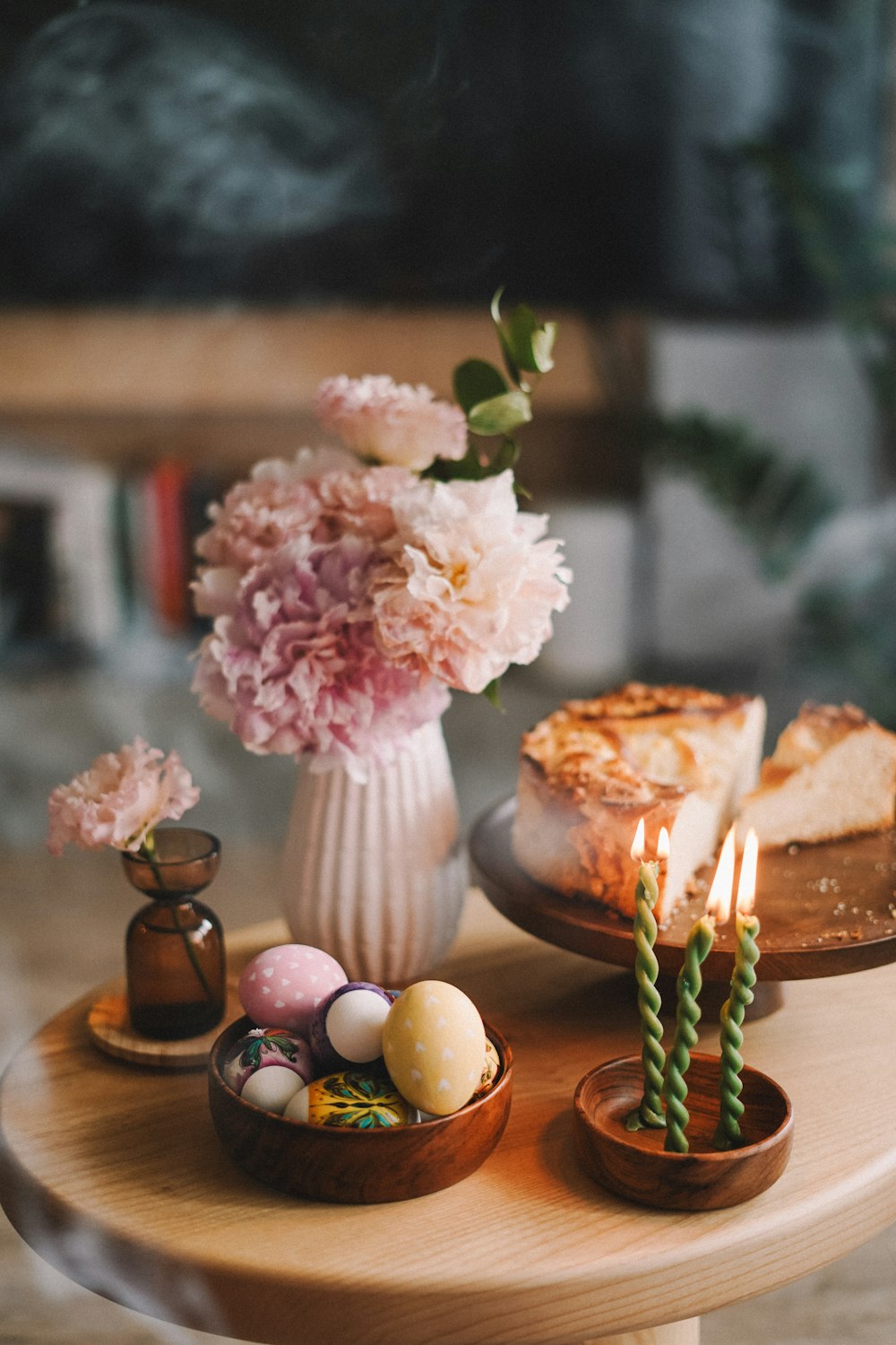 a table topped with a cake and a vase filled with flowers