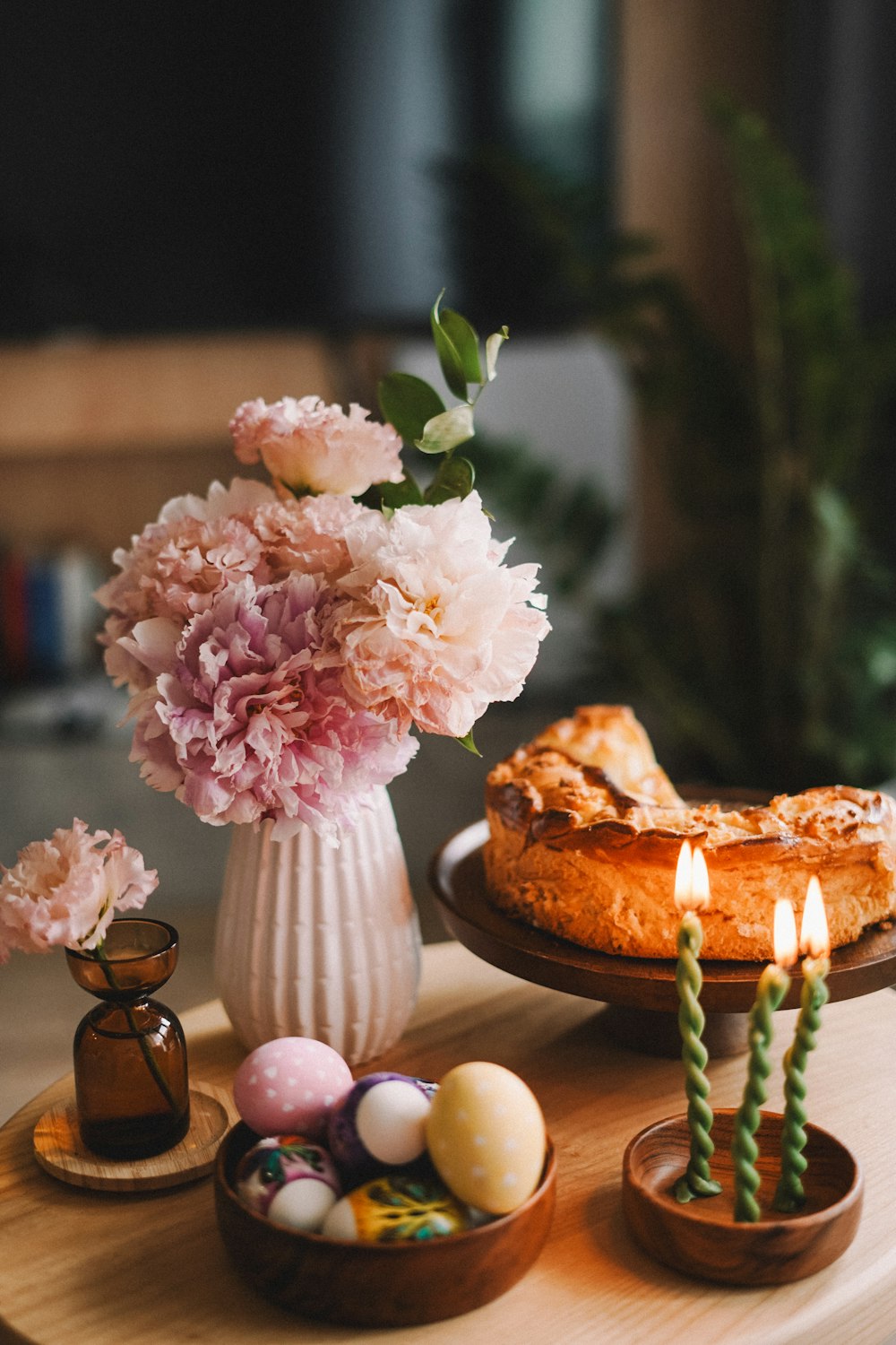 a table topped with a cake and a vase filled with flowers