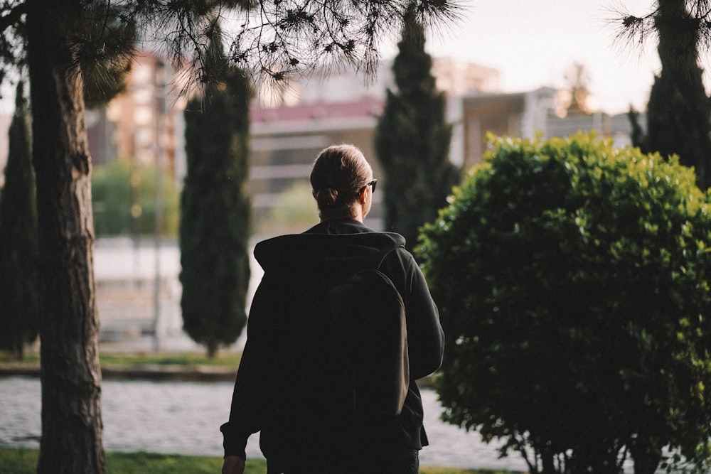 a man walking down a street next to trees