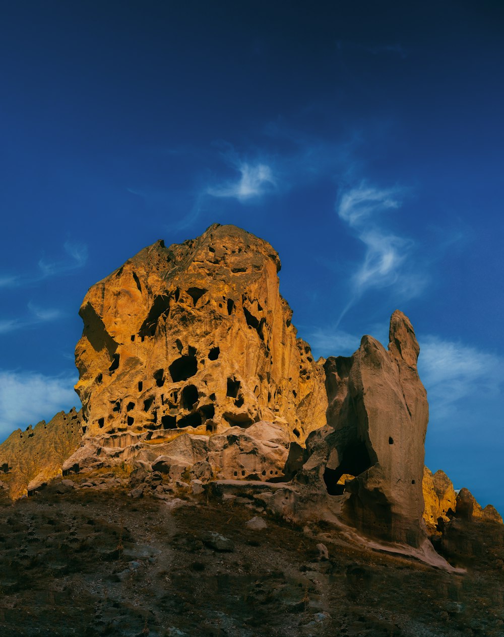 uma formação rochosa em uma colina com um céu azul ao fundo